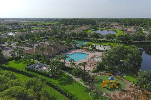 Aerial view of the community clubhouse, pool, playground, and surrounding lakes
