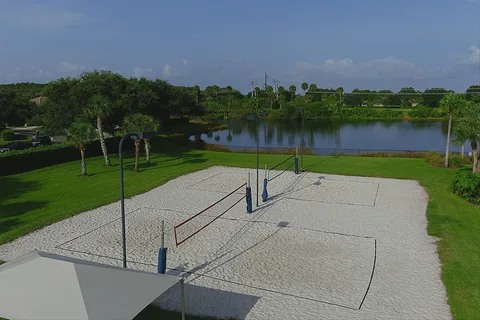 Sand volleyball courts set beside a lake and green space