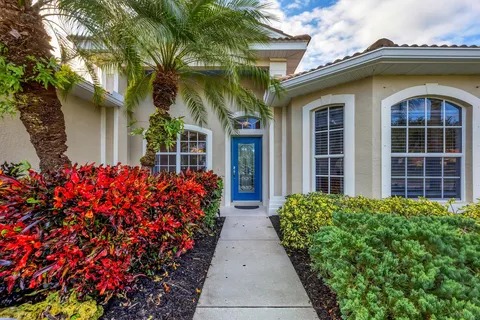 Front walkway and entry framed by palms and colorful tropical foliage