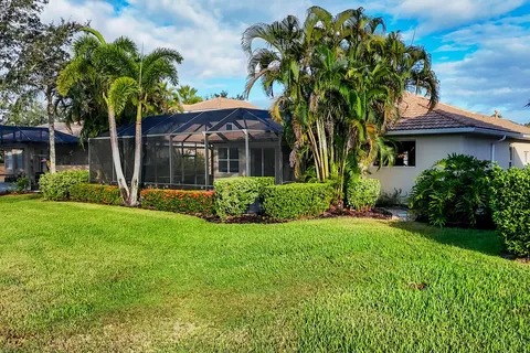 Rear exterior with screened pool lanai and lush green lawn