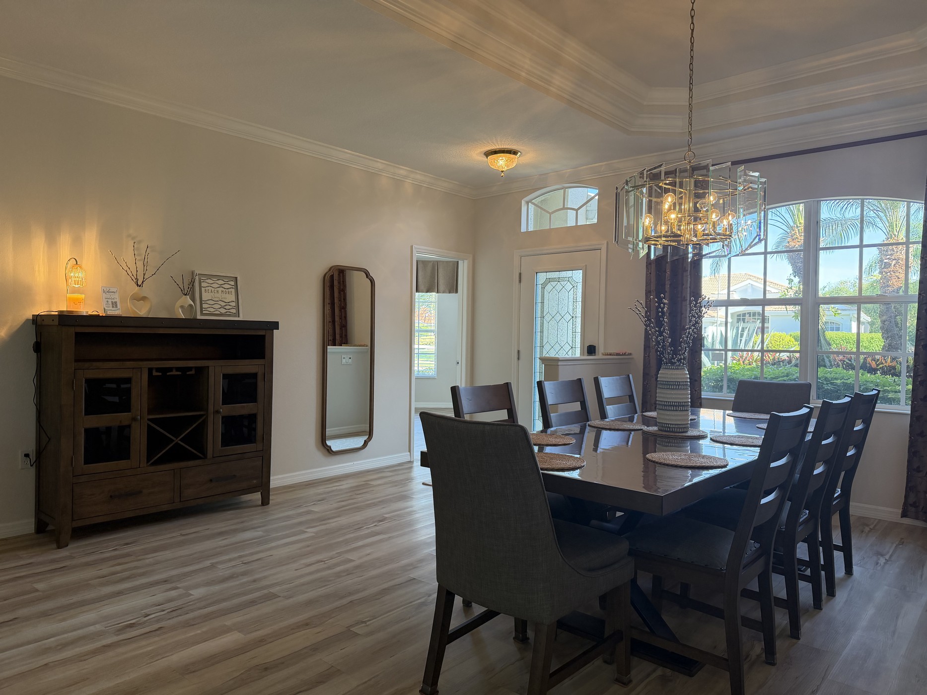Formal dining room with a large table, chandelier, and tropical garden views