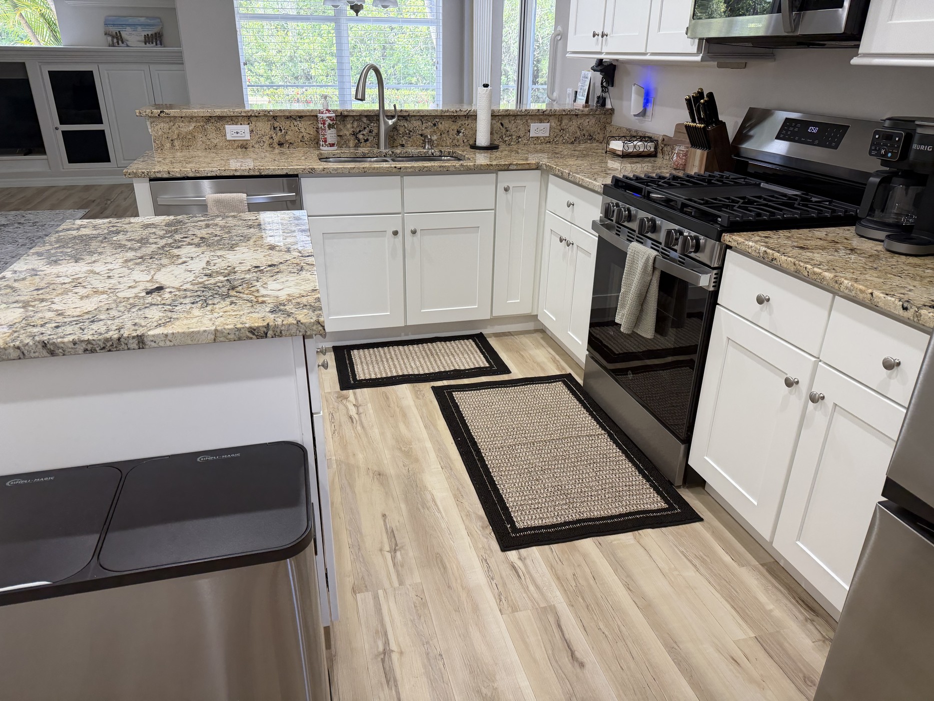 Kitchen work area with granite island, gas range, double sink, and dishwasher
