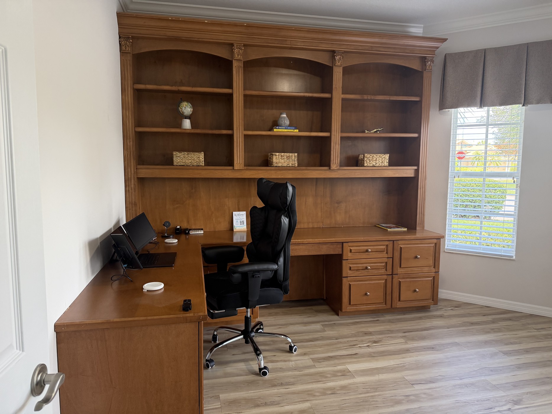 Private home office with a large built-in desk, shelving, and ergonomic chair