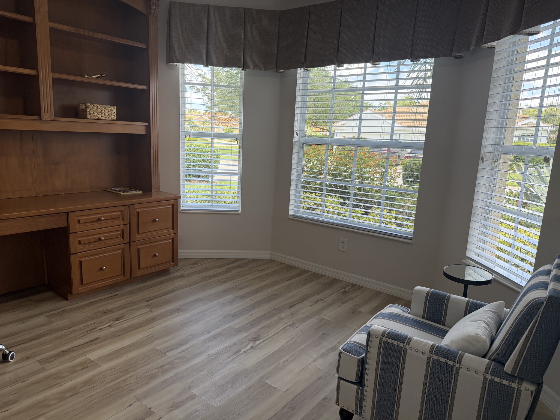 Bright office sitting area with three windows overlooking tropical landscaping