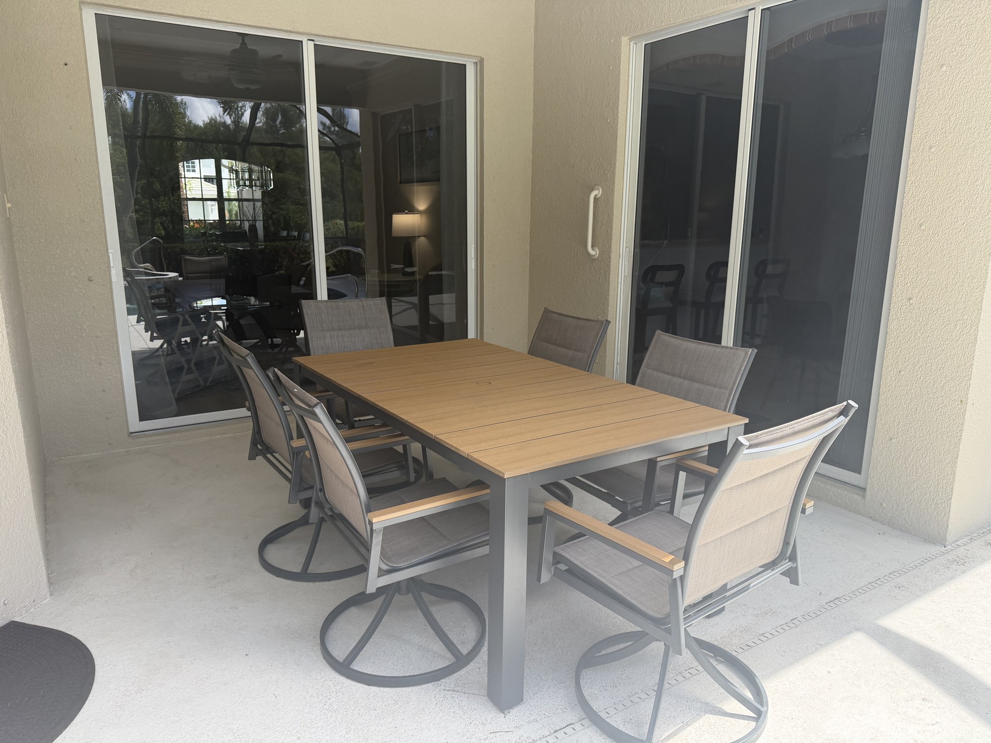Covered outdoor dining table and chairs beside sliding doors to the house