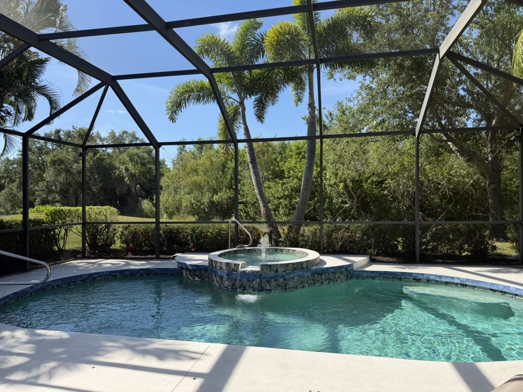 Screened private pool and raised spa surrounded by palms and tropical landscaping