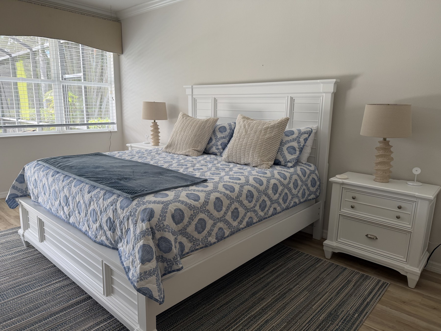 King bed with white coastal furniture and blue shell-patterned linens
