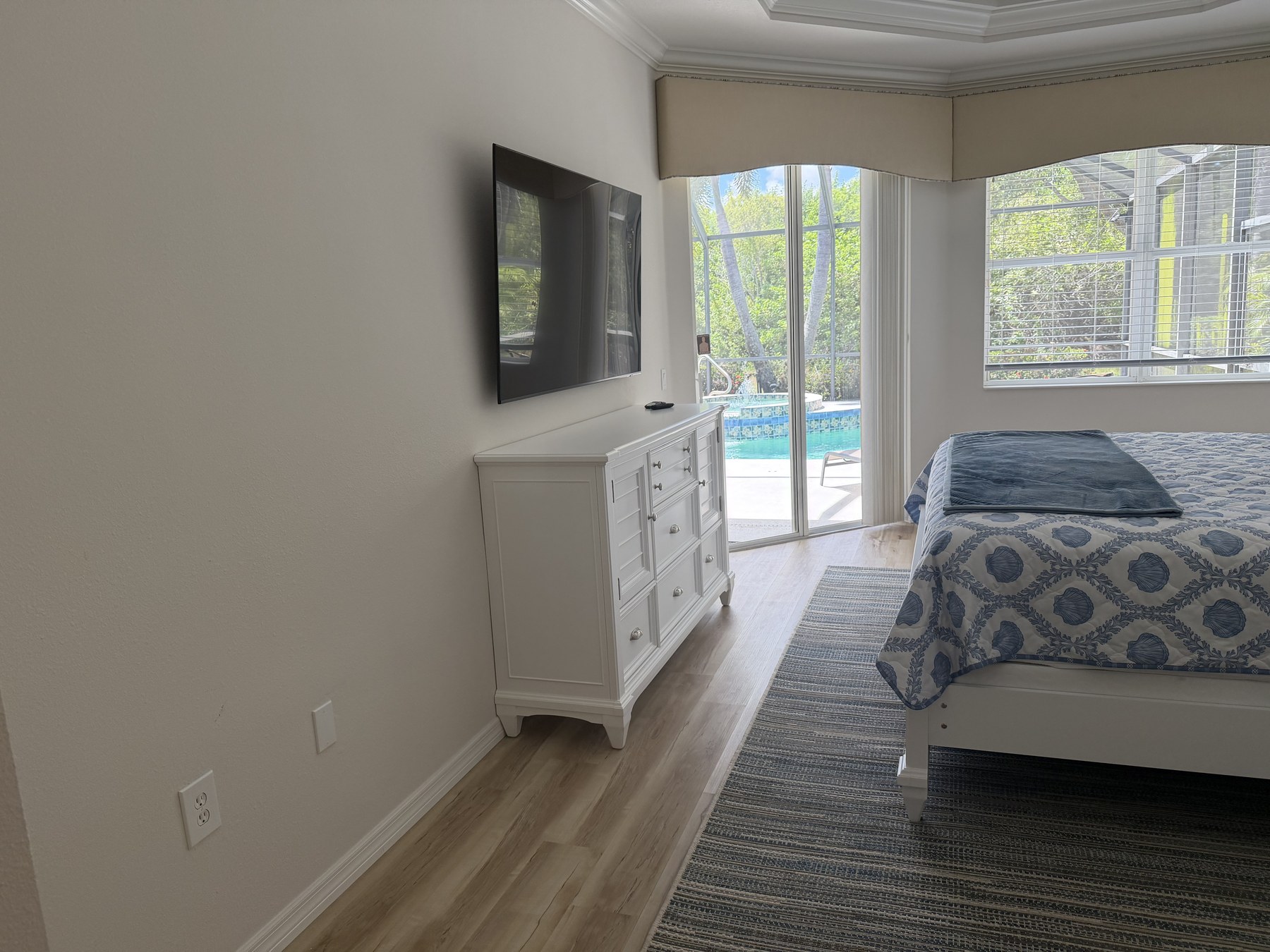 Primary suite television and sliding doors opening directly to the pool